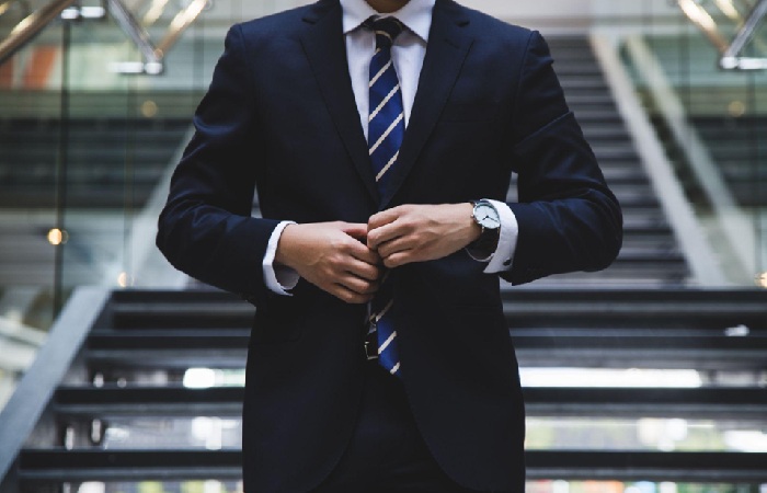 A business owner like the ones William Smith helps buttons his suit coat